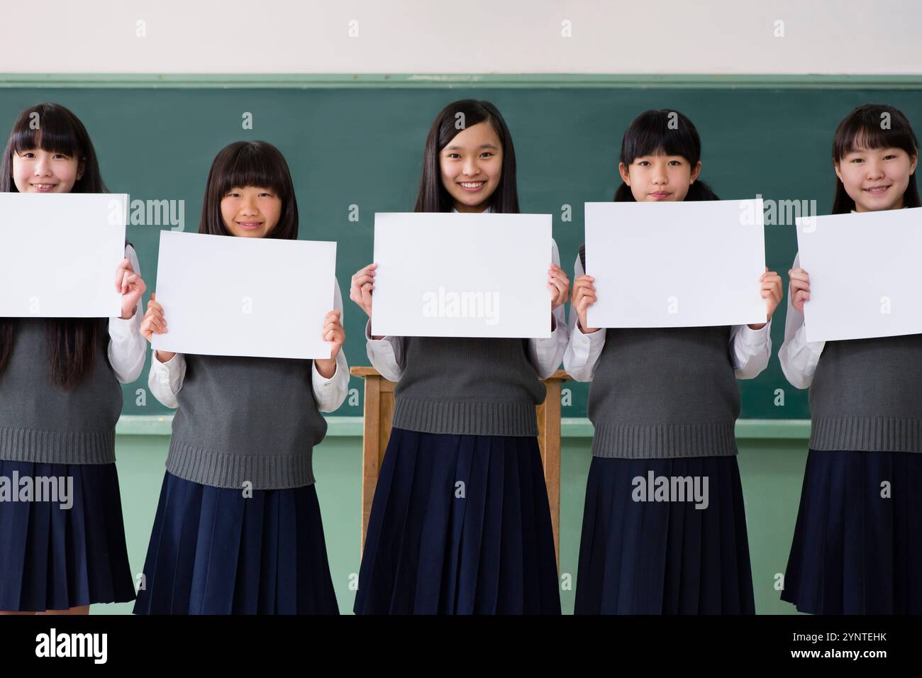 Studentinnen sitzen in einer Reihe und halten ein Brett in einem Klassenzimmer Stockfoto