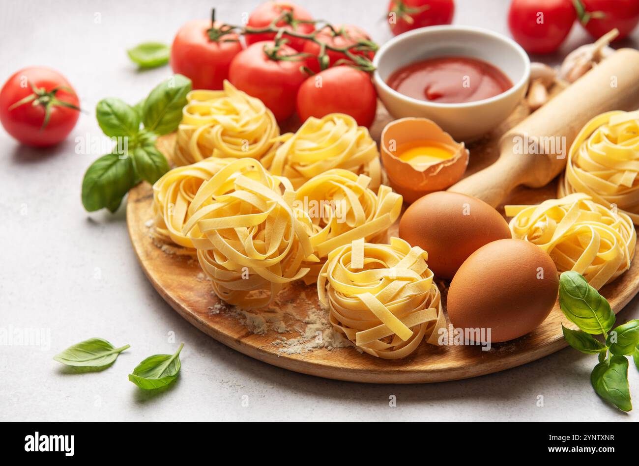 Tagliatelle nestet mit Zutaten auf Holzbrett und schafft eine einladende Szene für Liebhaber der italienischen Küche Stockfoto