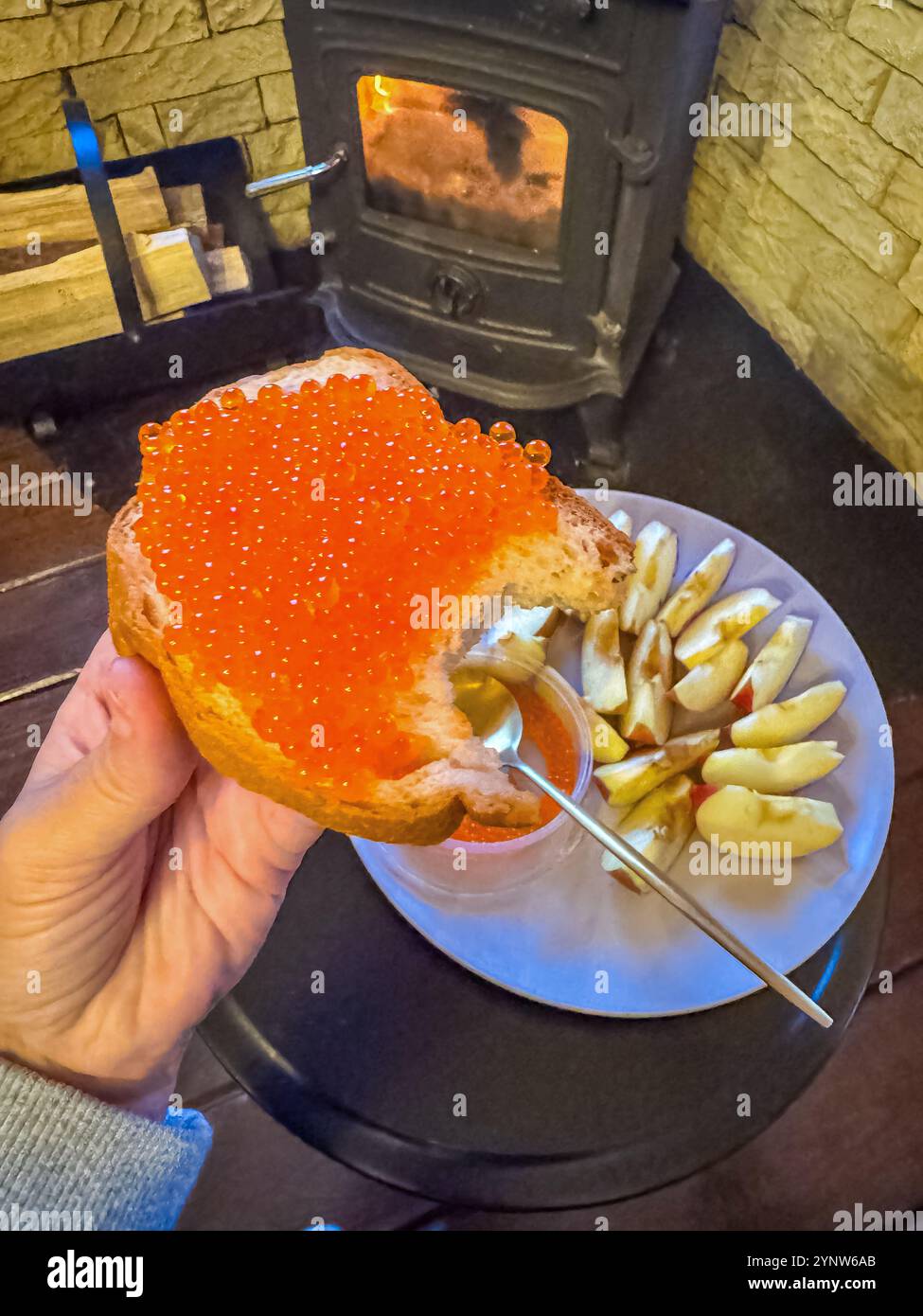 Gemütlicher Snack am Kamin Red Caviar auf Toast mit Äpfeln und warmer Atmosphäre. Hochwertige Fotos Stockfoto