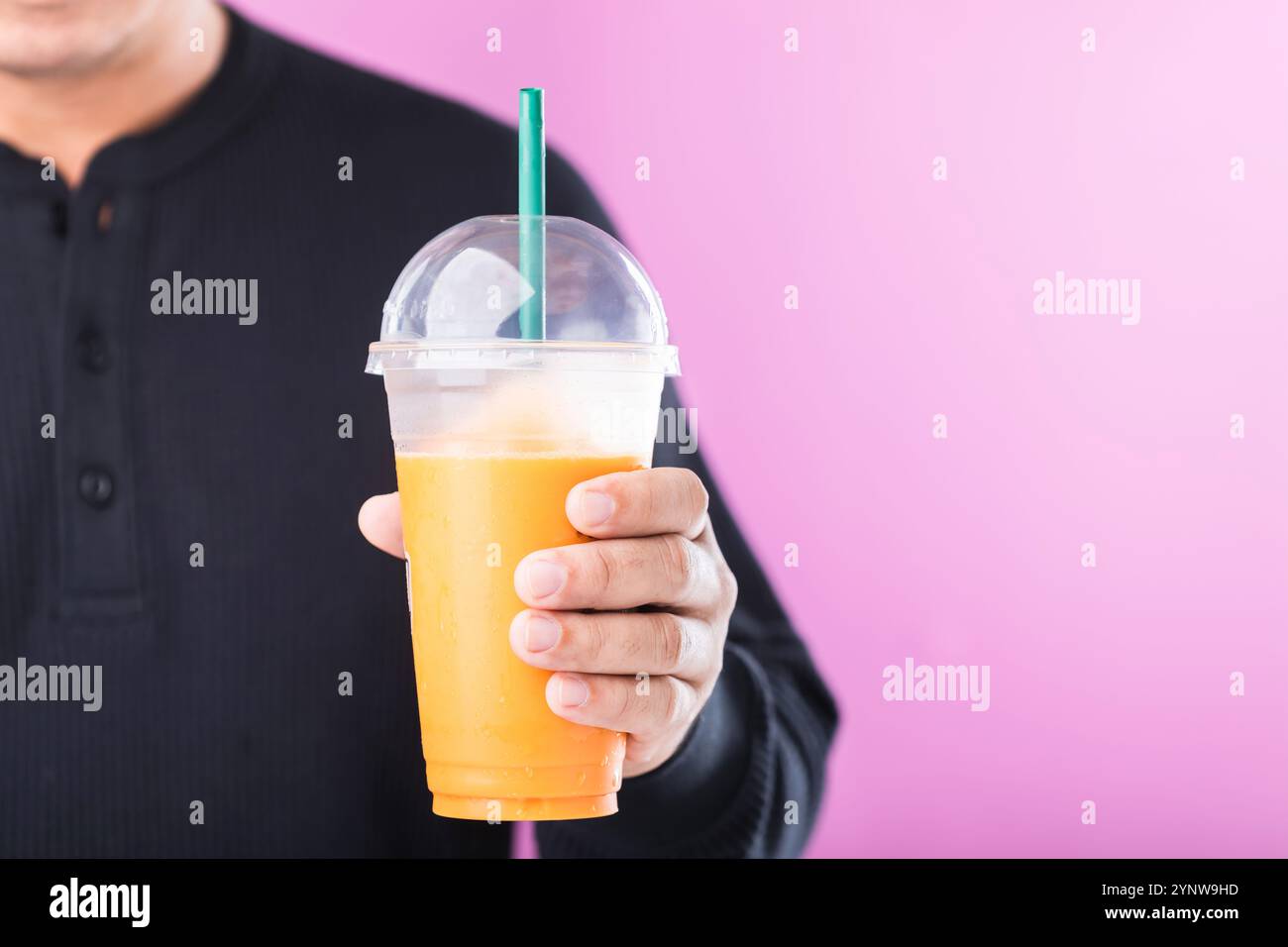 Ein Mann, der ein Glas thailändischen Milchtees genießt, symbolisiert den Reiz süßer Getränke. Hebt die potenziellen gesundheitlichen Risiken von zuckerhaltigen Getränken hervor, einschließlich von Getränken Stockfoto