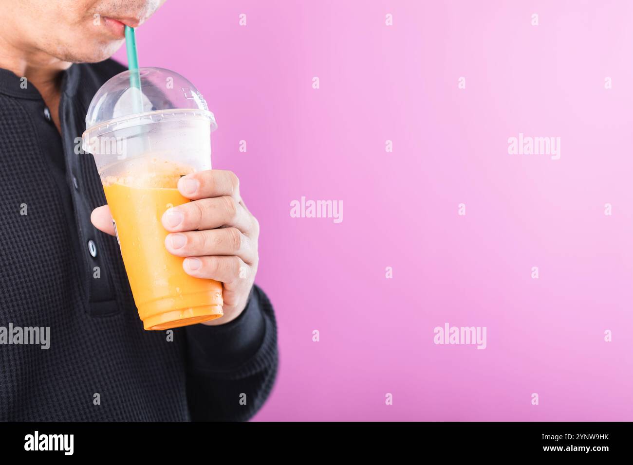 Ein Mann, der ein Glas thailändischen Milchtees genießt, symbolisiert den Reiz süßer Getränke. Hebt die potenziellen gesundheitlichen Risiken von zuckerhaltigen Getränken hervor, einschließlich von Getränken Stockfoto