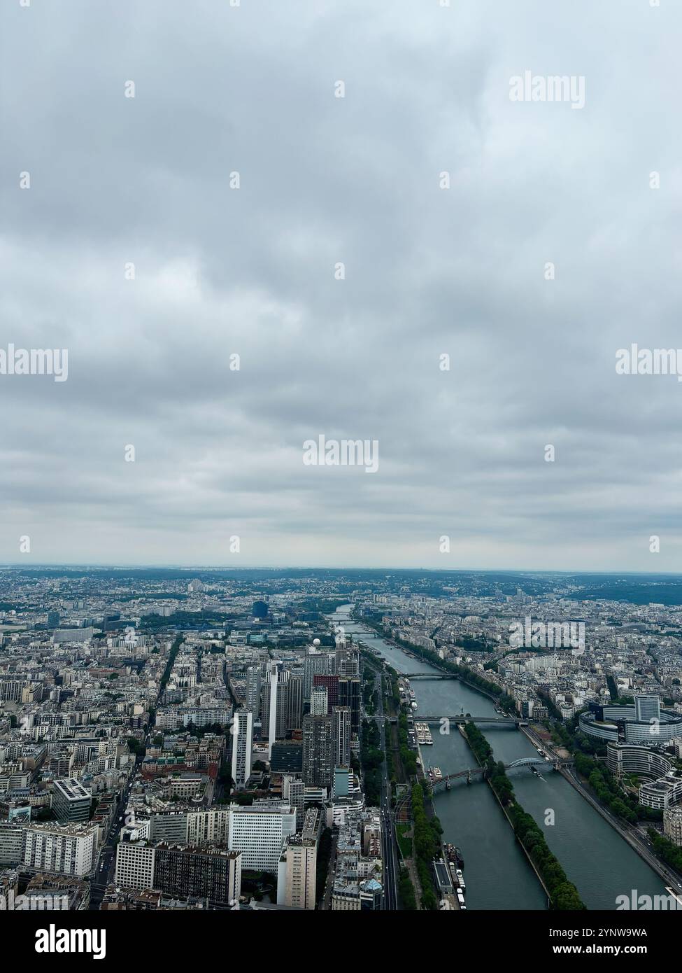 Ein atemberaubender Blick aus der Luft auf Paris mit Blick auf die seine, die sich unter einem dramatischen bewölkten Himmel durch die Stadt schlängelt und urbane Architektur und l Stockfoto