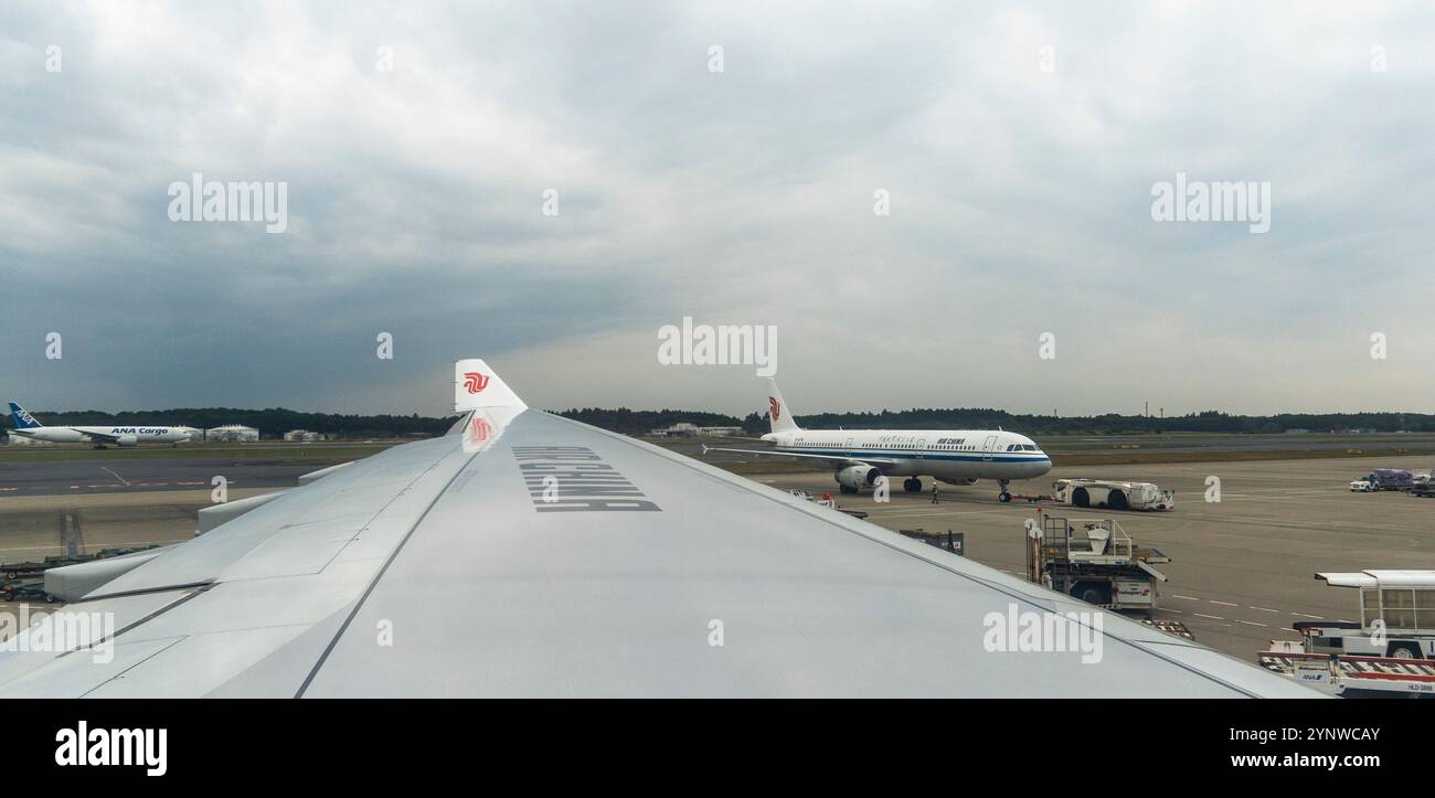 Der bewölkte Himmel umrahmt die geschäftige Flughafenszene mit Flugzeugen, die auf den Abflug warten Stockfoto Der bewölkte Himmel umrahmt die geschäftige Flughafenszene mit Flugzeugen, die auf den Abflug warten Stockfoto