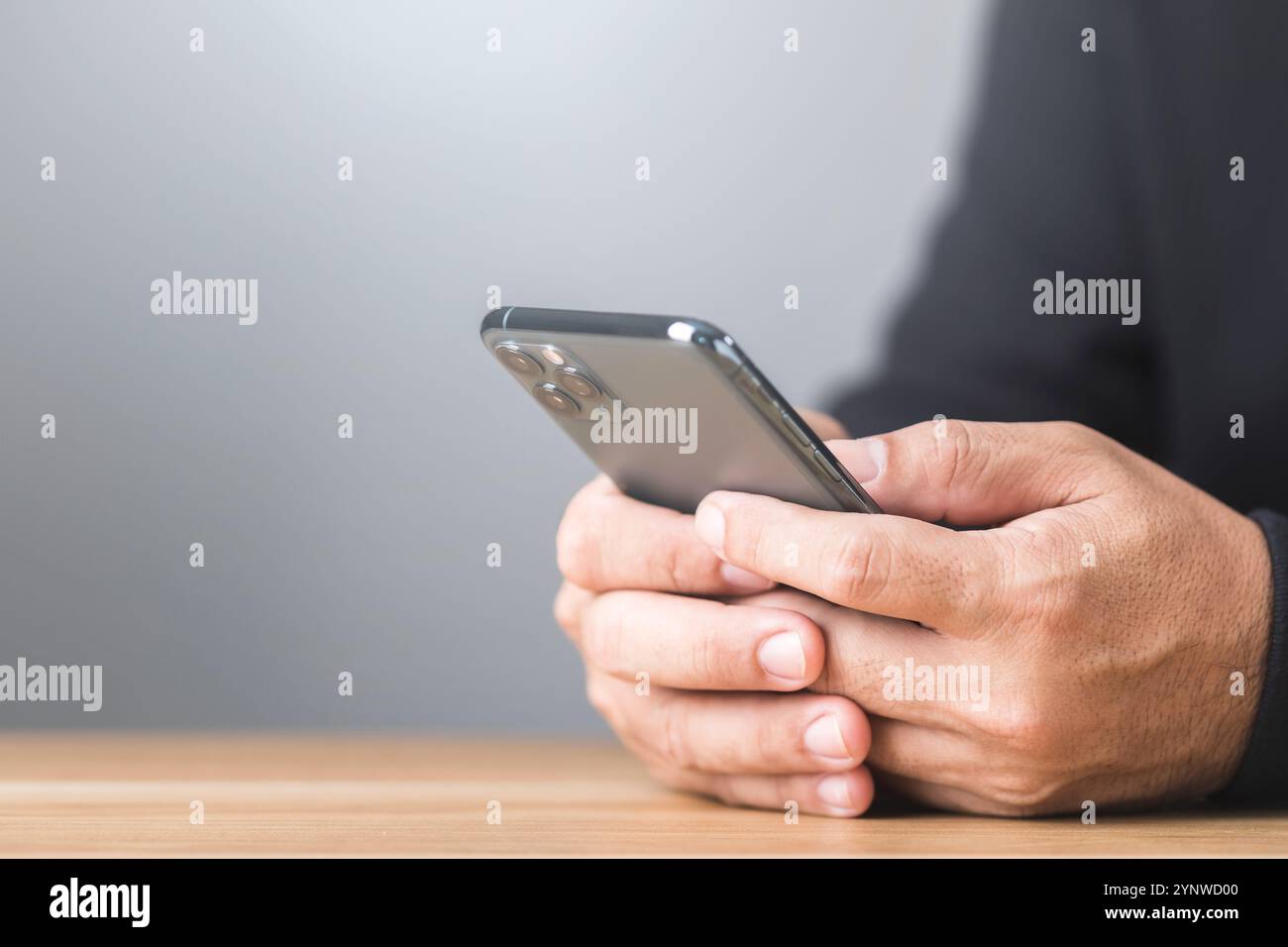 Ein Mann tippt auf seinem Smartphone, der an einem privaten Online-Chat teilnimmt. Die Nahansicht unterstreicht die diskrete Art des Gesprächs und spiegelt die Sicherheit wider Stockfoto