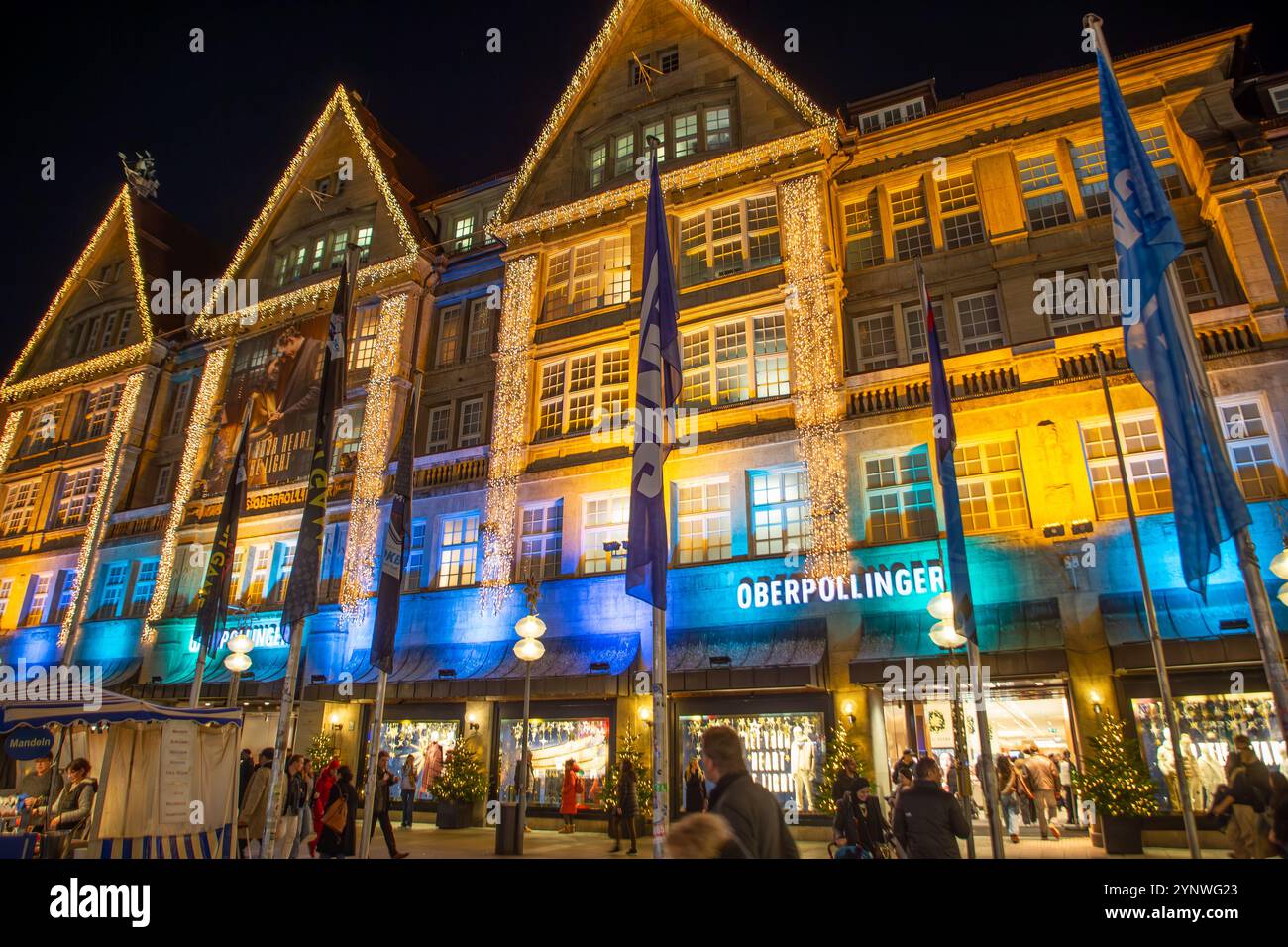 München, Deutschland - 17. November 2024: Fassade des alten traditionellen Einkaufszentrums Operpollinger in München bei Nacht. Stockfoto