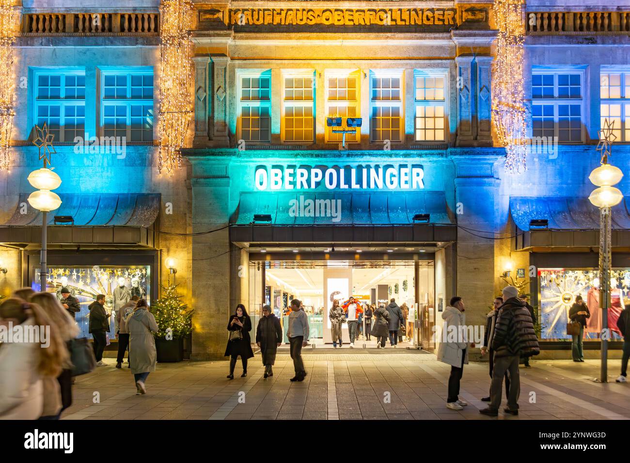 München, Deutschland - 17. November 2024: Fassade des alten traditionellen Einkaufszentrums Operpollinger in München bei Nacht. Stockfoto