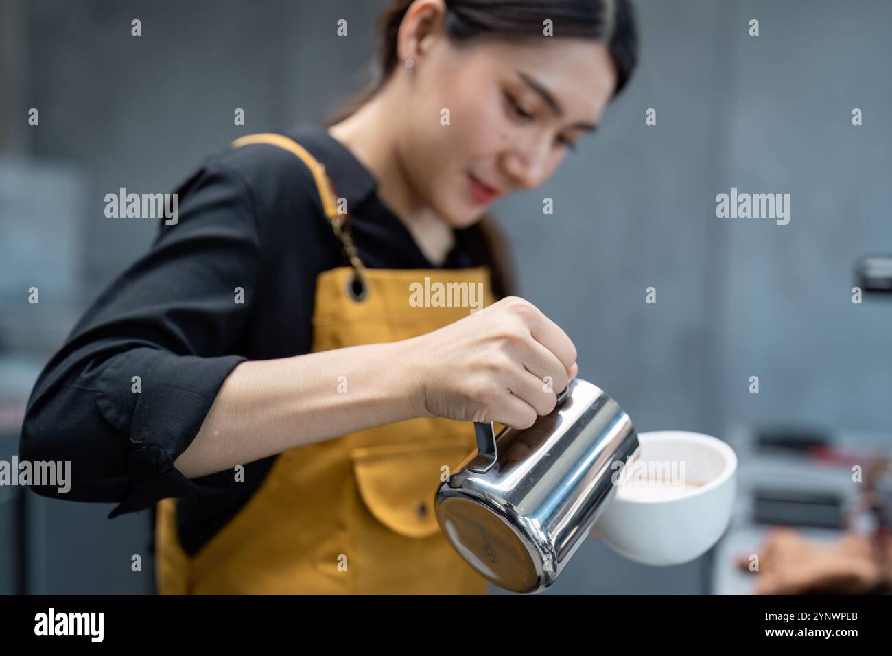 Junger Barista im modernen Coffee Shop bereitet eine frische Tasse Kaffee für Gäste in einer Startup-Umgebung für kleine Unternehmen vor Stockfoto