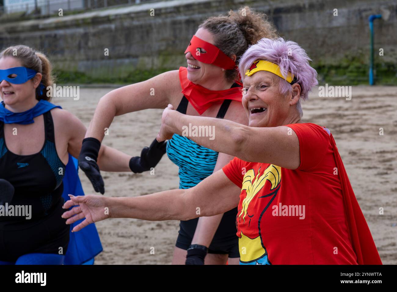 Die Teilnehmer treffen sich am Strand von Towan und bereiten sich auf die jährliche Veranstaltung „Superhero in the Cold“ vor, um Spenden für die britische Krebsforschung zu sammeln. Stockfoto