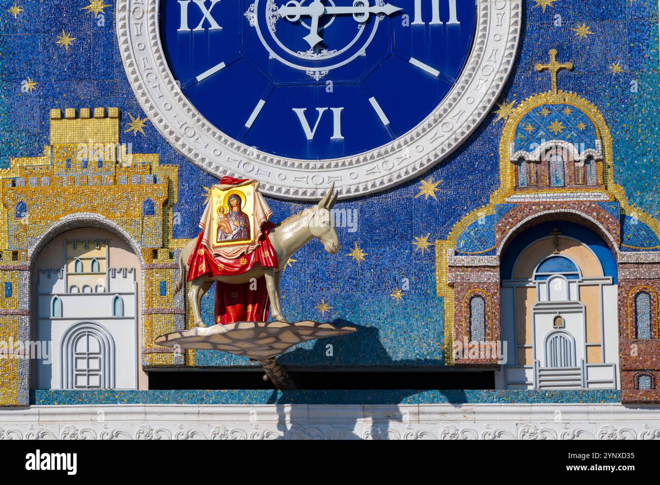 JOSCHKAR-OLA, RUSSLAND – 31. AUGUST 2024: Ein Esel trägt dreihändig das Symbol der Mutter Gottes. Fragment der dynamischen Uhr auf dem Turm der N Stockfoto