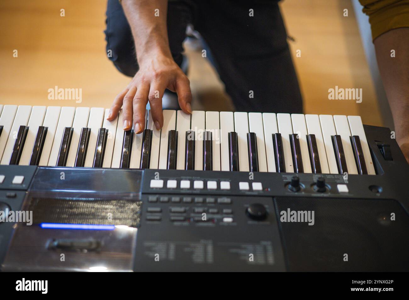 Nahaufnahme von Händen, die eine digitale Tastatur bei warmem Tageslicht spielen, um die Essenz von Kreativität, Fokus und musikalischer Leidenschaft in einer intimen Atmosphäre festzuhalten Stockfoto