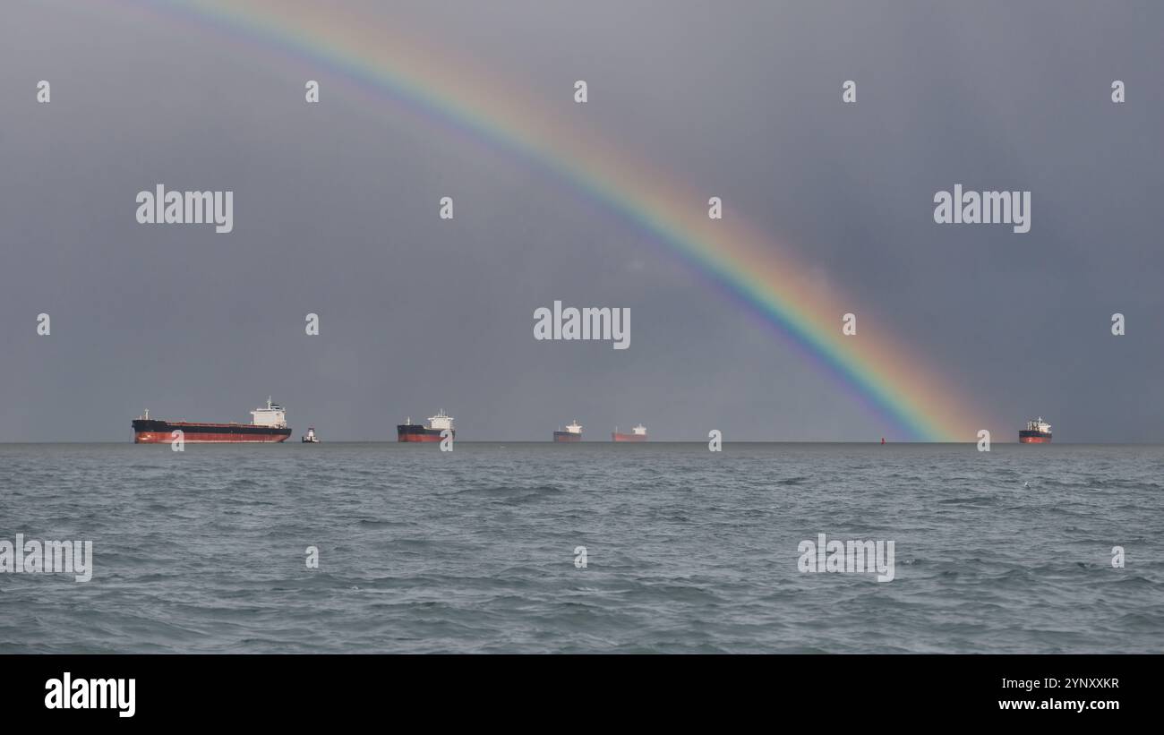 Rainbow über sechs Frachtschiffe, die am Horizont des Pazifischen Ozeans segeln, USA Stockfoto