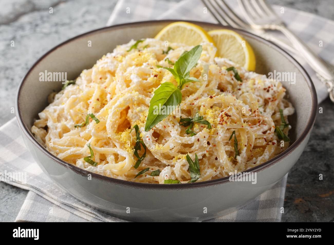 Italienische Pasta mit Ricotta, Parmesan, nativem Olivenöl extra, Knoblauch, Zitronenschale, Basilikum und Pfeffer auf dem Teller auf dem Tisch. Horizontal Stockfoto