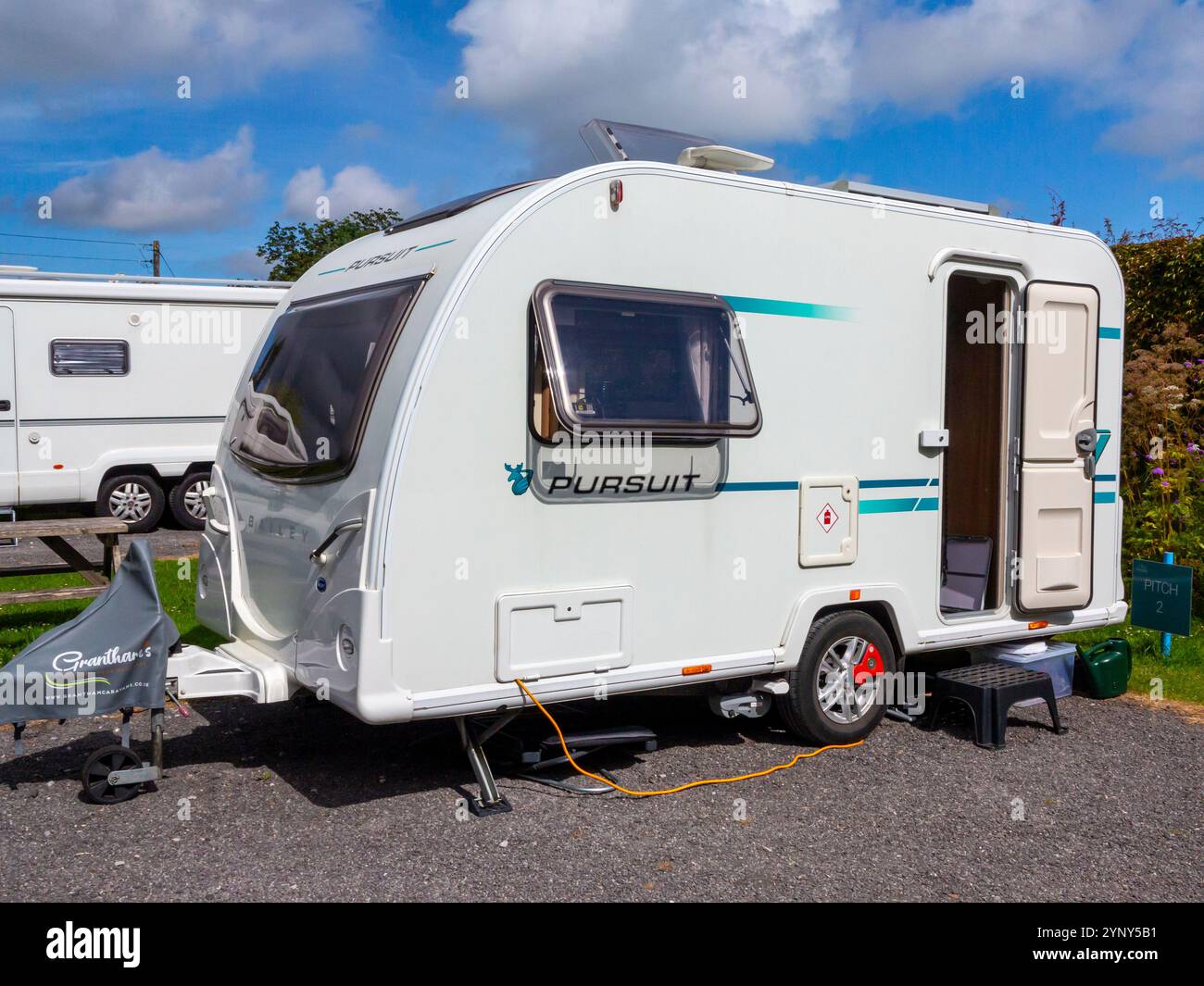 Bailey Pursuit 400-2 Tourenwagen mit zwei Liegeplätzen auf einem Platz auf einem Wohnwagenplatz im Sommer mit blauem Himmel und Wolken darüber. Stockfoto