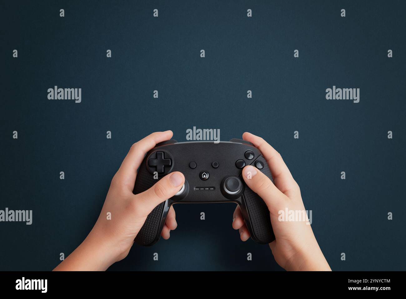 Draufsicht einer Hand, die ein Gamepad auf einem blauen Schreibtisch hält, flache Komposition mit sauberem Platz für Werbetexte, ideal für Spiele und technisches Branding Stockfoto