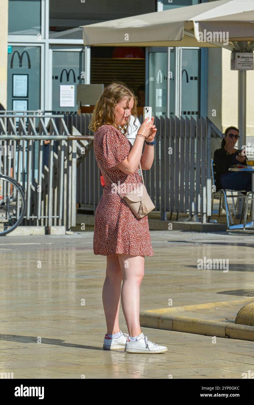 Junge Frau, die ihr Handy benutzt, um Fotos zu machen, während sie in Frankreich Urlaub macht Stockfoto