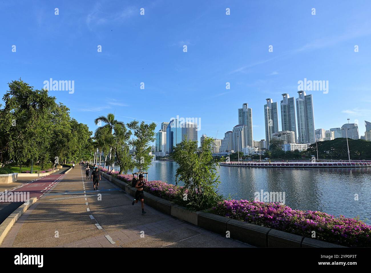 Menschen laufen am frühen Morgen auf dem Trainingsplatz entlang des Lake Ratchada im Benjakitti Park, einem sehr beliebten Erholungsort im Zentrum von Bangkok Stockfoto