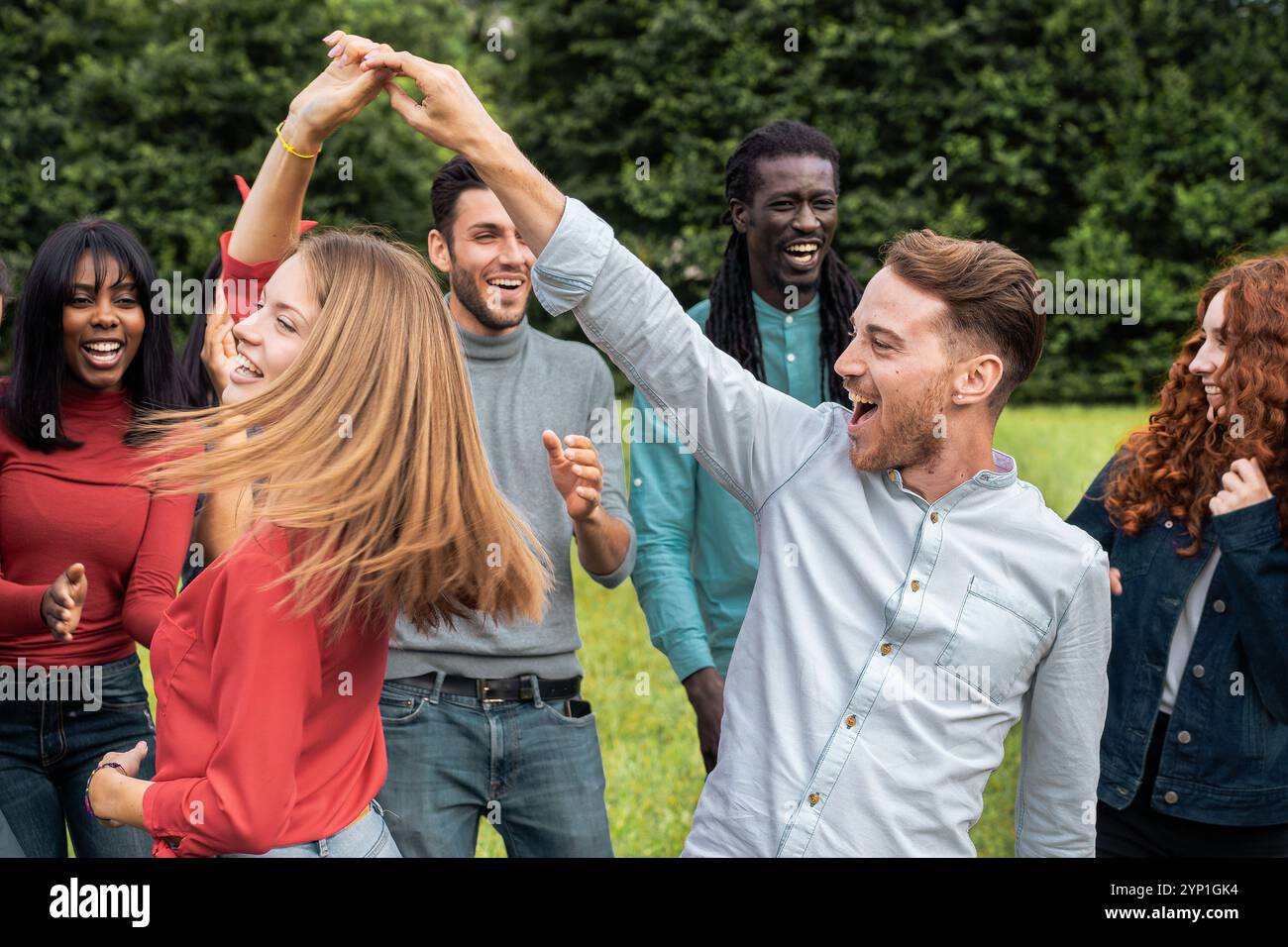 Dynamisches Porträt verschiedener junger Freunde, die im Freien tanzen und miteinander wirbeln. Authentische Lifestyle-Aufnahmen, die echte Freude, Bewegung und Multik zeigen Stockfoto