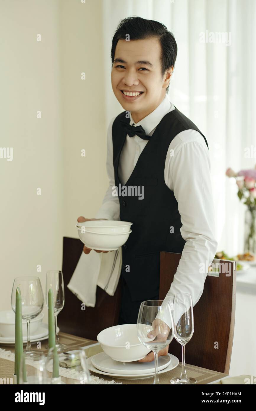Lächelnder Kellner, der den Tisch im Restaurant aufstellte Stockfoto