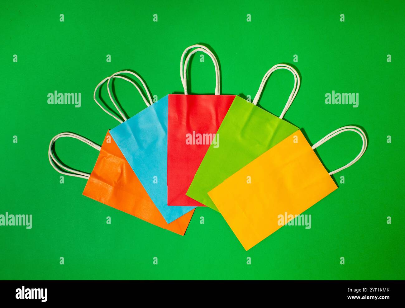 Bunte, leuchtende Papiertüten auf grünem Hintergrund Stockfoto