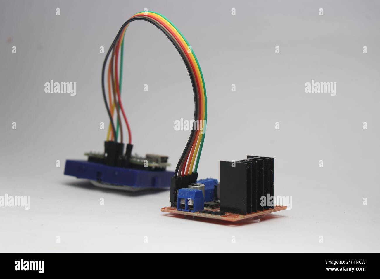 Der Motorcontroller ist über Überbrückungskabel auf weißem Hintergrund mit dem Mikrocontroller auf der Steckplatine verbunden Stockfoto