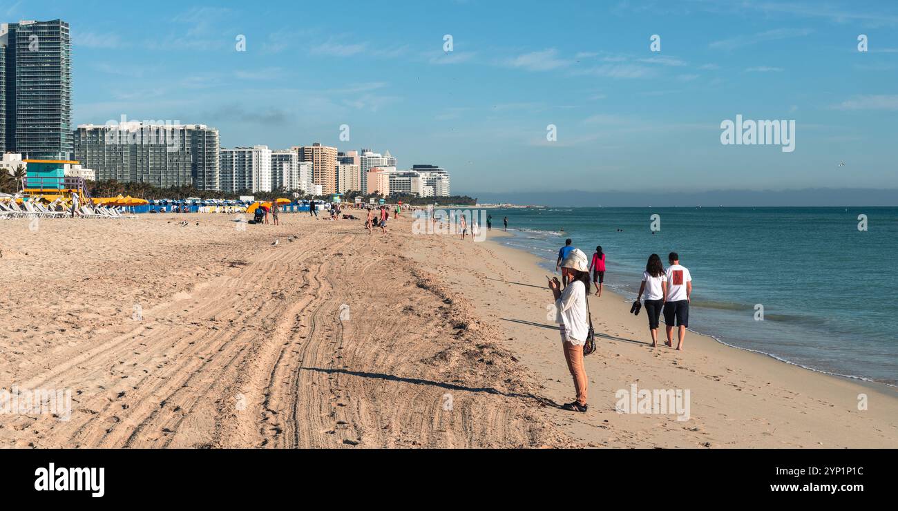 Miami Beach, USA - 29. Dezember 2017: Touristen schlendern in der Nebensaison an einem ruhigen Strand entlang. Stockfoto