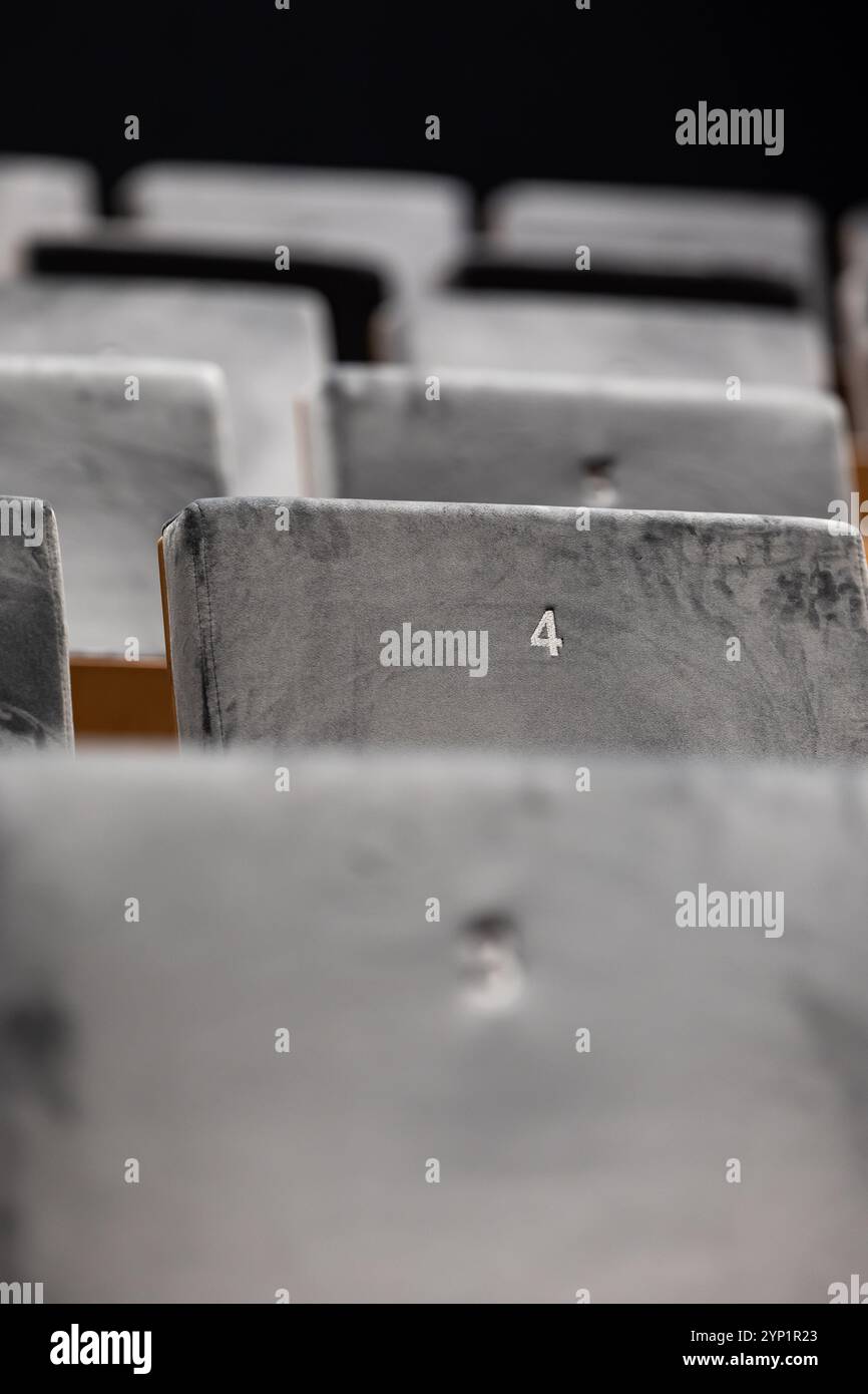 Reihen leerer Sitze in einem Kinosaal, Vorderseite der Sitze mit Nummern. Nahaufnahme mit geringer Schärfentiefe Stockfoto