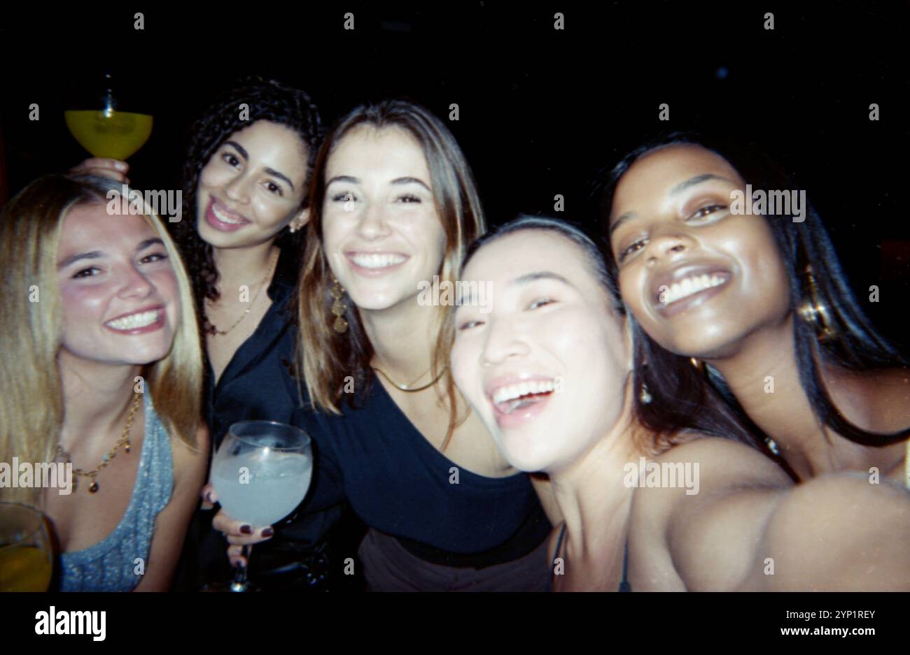Eine Gruppe glücklicher Freunde posiert zusammen in einer lebhaften Atmosphäre, aufgenommen mit einem Vintage-Film-Look, mit staubigen und zerkratzten Effekten für einen nostalgischen Look Stockfoto