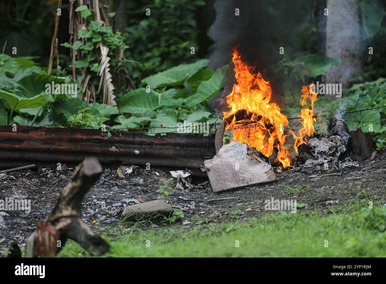 Laguna, Philippinen. 28. November 2024: Müllfeuer am Rande eines Waldes. Viele Filipinos verbrennen Müll in Hinterhöfen, eine häufige Ursache für Fehden in der Nachbarschaft. Das Gesetz verbietet offenes Abbrennen, aber diese umweltschädliche und schädliche Praxis namens „Pagsisiga“ ist in ländlichen Gebieten weit verbreitet. Dämpfe und Verbrennungsrückstände von Haushaltsabfällen, Elektronik, Kunststoff, Synthetik, Chemie, Pappe, organische Materialien verschmutzen Umwelt, Grundwasser und Luft. Die fünfte Sitzung des zwischenstaatlichen Verhandlungsausschusses für Kunststoffverschmutzung (INC-5) findet diese Woche in Südkorea statt. Quelle: Kevin Izorce/Alamy Live News Stockfoto
