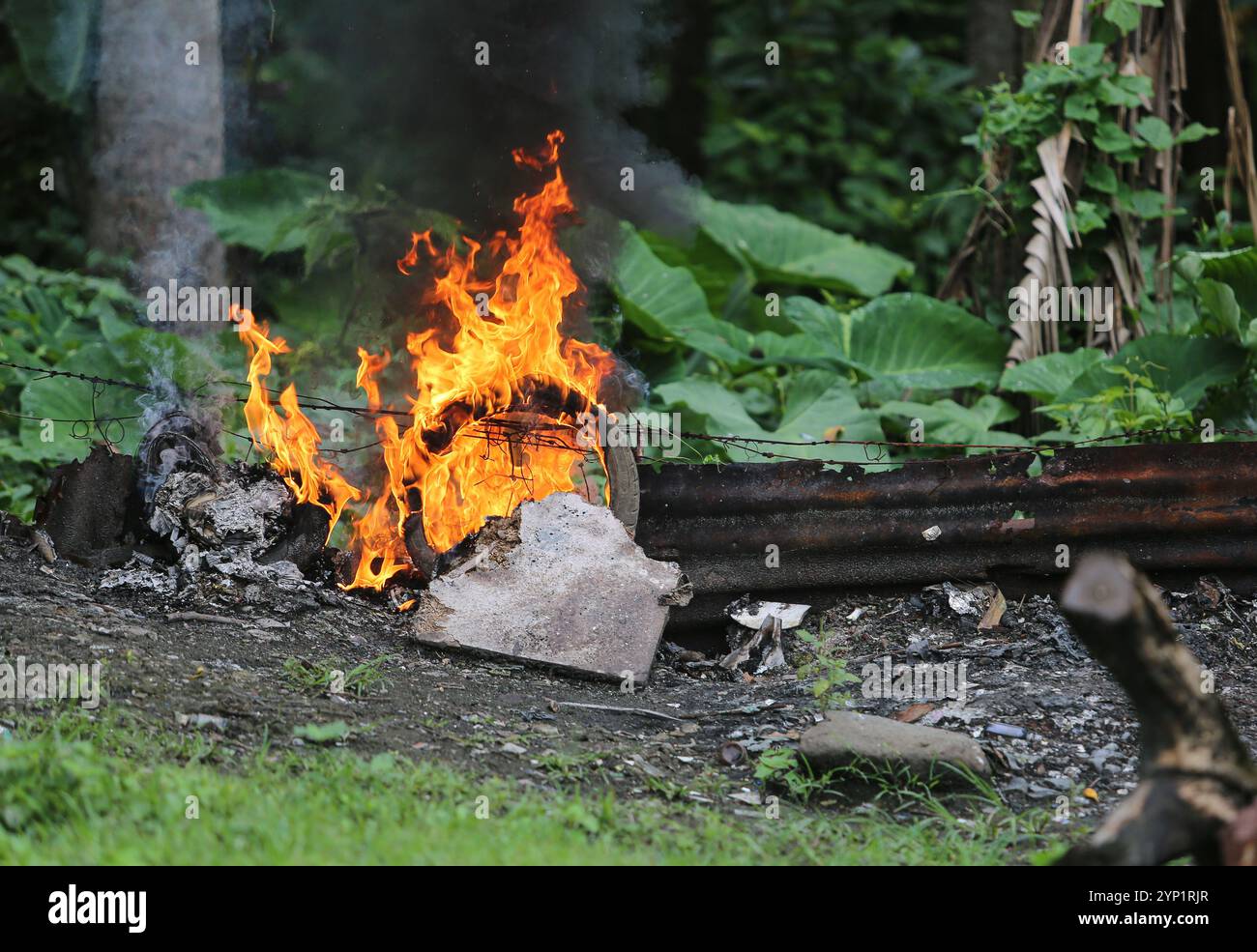 Laguna, Philippinen. 28. November 2024: Müllfeuer am Rande eines Waldes. Viele Filipinos verbrennen Müll in Hinterhöfen, eine häufige Ursache für Fehden in der Nachbarschaft. Das Gesetz verbietet offenes Abbrennen, aber diese umweltschädliche und schädliche Praxis namens „Pagsisiga“ ist in ländlichen Gebieten weit verbreitet. Dämpfe und Verbrennungsrückstände von Haushaltsabfällen, Elektronik, Kunststoff, Synthetik, Chemie, Pappe, organische Materialien verschmutzen Umwelt, Grundwasser und Luft. Die fünfte Sitzung des zwischenstaatlichen Verhandlungsausschusses für Kunststoffverschmutzung (INC-5) findet diese Woche in Südkorea statt. Quelle: Kevin Izorce/Alamy Live News Stockfoto