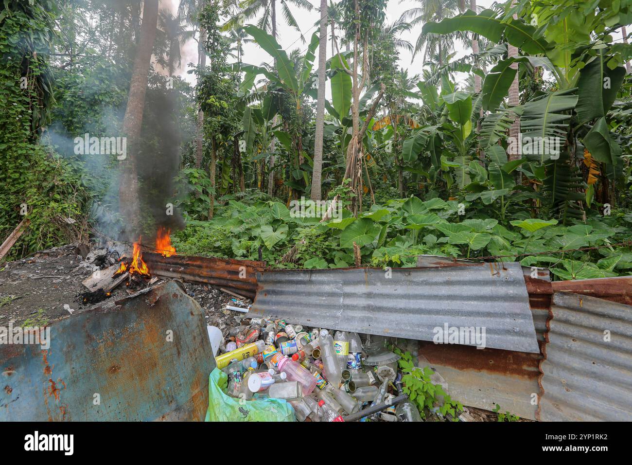 Laguna, Philippinen. 28. November 2024: Müllfeuer am Rande eines Waldes. Viele Filipinos verbrennen Müll in Hinterhöfen, eine häufige Ursache für Fehden in der Nachbarschaft. Das Gesetz verbietet offenes Abbrennen, aber diese umweltschädliche und schädliche Praxis namens „Pagsisiga“ ist in ländlichen Gebieten weit verbreitet. Dämpfe und Verbrennungsrückstände von Haushaltsabfällen, Elektronik, Kunststoff, Synthetik, Chemie, Pappe, organische Materialien verschmutzen Umwelt, Grundwasser und Luft. Die fünfte Sitzung des zwischenstaatlichen Verhandlungsausschusses für Kunststoffverschmutzung (INC-5) findet diese Woche in Südkorea statt. Quelle: Kevin Izorce/Alamy Live News Stockfoto