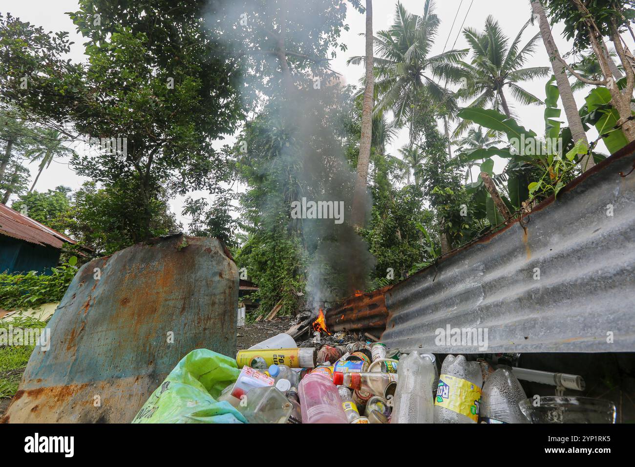 Laguna, Philippinen. 28. November 2024: Müllfeuer am Rande eines Waldes. Viele Filipinos verbrennen Müll in Hinterhöfen, eine häufige Ursache für Fehden in der Nachbarschaft. Das Gesetz verbietet offenes Abbrennen, aber diese umweltschädliche und schädliche Praxis namens „Pagsisiga“ ist in ländlichen Gebieten weit verbreitet. Dämpfe und Verbrennungsrückstände von Haushaltsabfällen, Elektronik, Kunststoff, Synthetik, Chemie, Pappe, organische Materialien verschmutzen Umwelt, Grundwasser und Luft. Die fünfte Sitzung des zwischenstaatlichen Verhandlungsausschusses für Kunststoffverschmutzung (INC-5) findet diese Woche in Südkorea statt. Quelle: Kevin Izorce/Alamy Live News Stockfoto