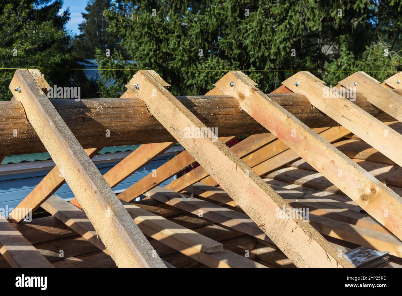 Das Holzdach befindet sich im Bau. Hintergrundfoto mit Sparren und Balken, selektiver Weichfokus Stockfoto