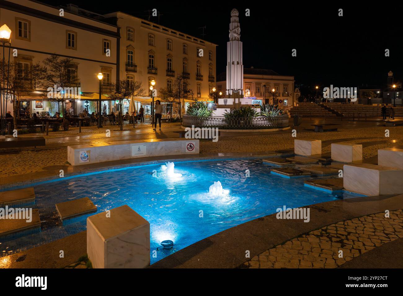 Hauptplatz mit Kopfsteinpflaster (Praca da República) bei Nacht mit beleuchtetem Brunnen, Tavira, Algarve, Portugal Stockfoto