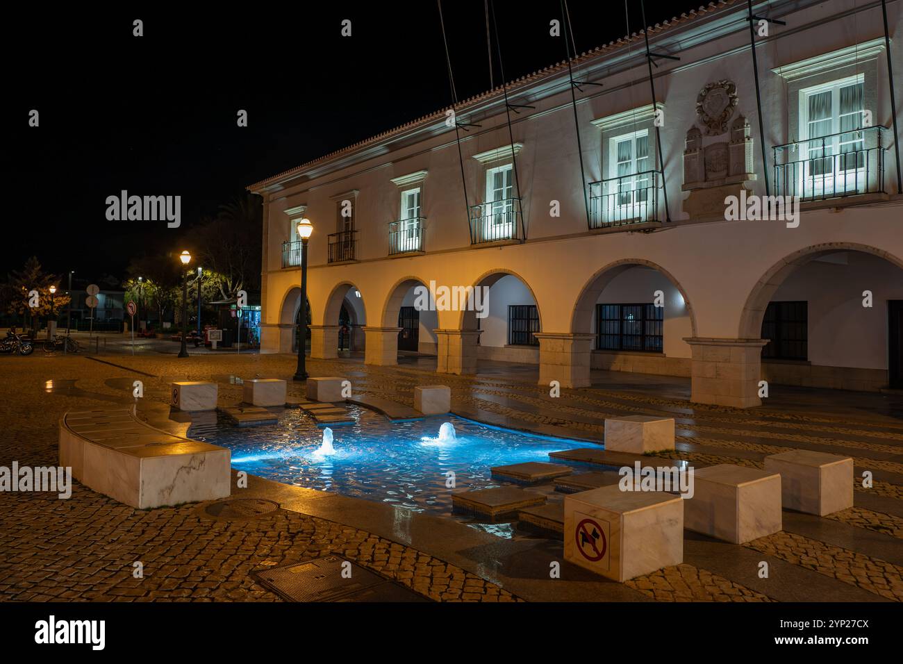 Hauptplatz mit Kopfsteinpflaster (Praca da República) bei Nacht mit beleuchtetem Brunnen, Tavira, Algarve, Portugal Stockfoto