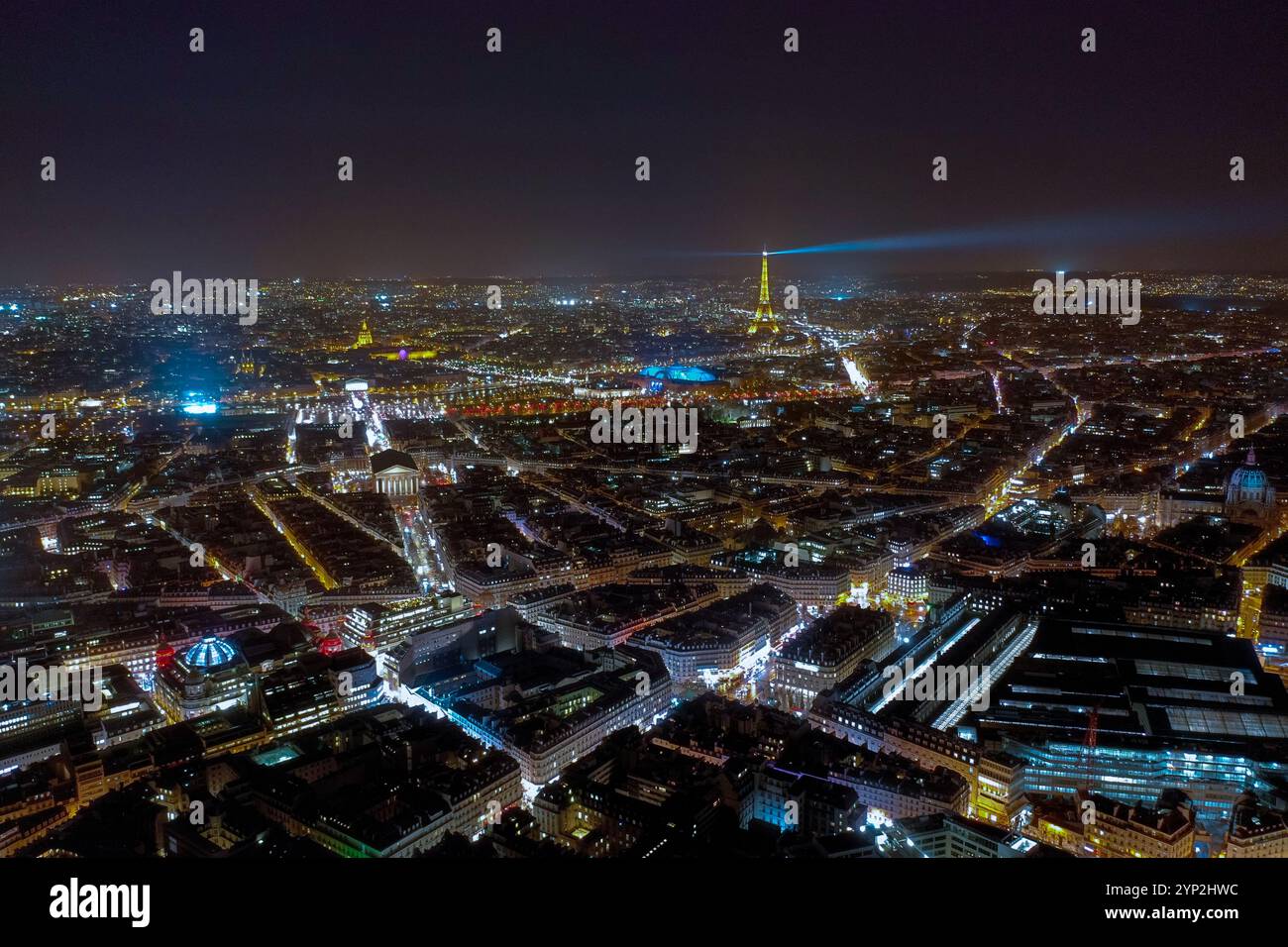 Atemberaubender nächtlicher Luftanblick auf Paris, beleuchtet von pulsierenden Lichtern der Stadt, mit goldenem Glanz und Leuchtfeuer des Eiffelturms über der urbanen Landschaft Stockfoto