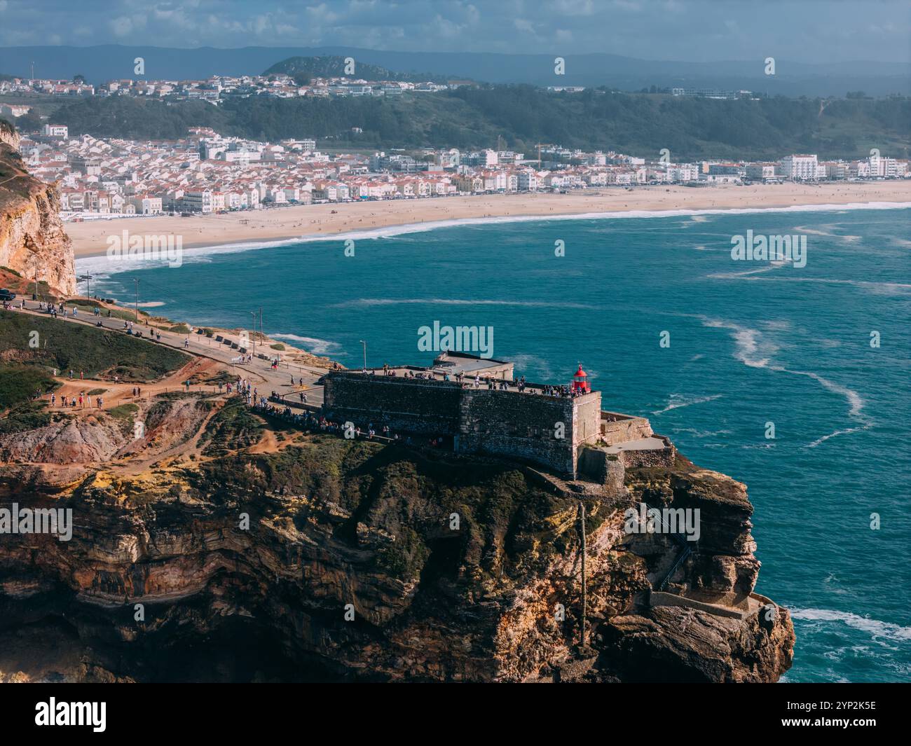 Blick auf Touristen aus der Vogelperspektive des historischen Leuchtturms Sao Miguel Arcanjo mit Blick auf die atemberaubende Küste von Nazare mit riesigen Wellen und spektakuläre V Stockfoto