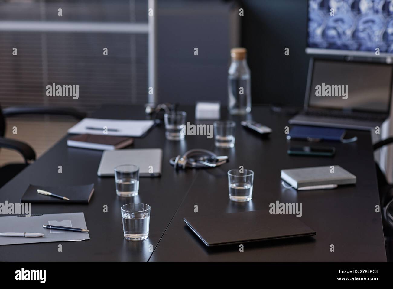 Hintergrundaufnahme eines geschlossenen Laptops, der auf dem Besprechungstisch mit Wassergläsern für Seminarteilnehmer im medizinischen Büro, Kopierraum platziert wurde Stockfoto