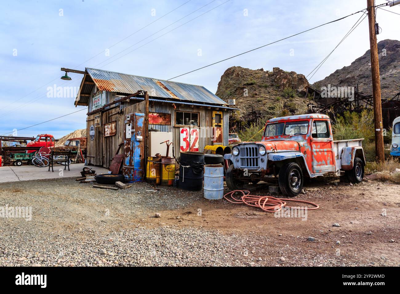 Ein alter roter Truck steht vor einem rustikalen Gebäude. Der Lkw steht vor einem Gebäude, auf dem ein Schild mit der Aufschrift 32 steht Stockfoto