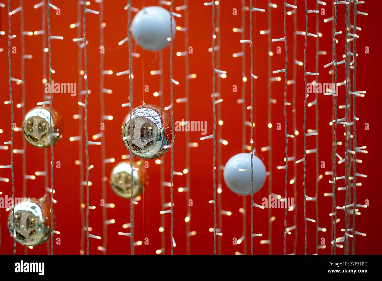 Weihnachtsbaumkugeln und -Girlanden hängen auf rotem Hintergrund. Stockfoto