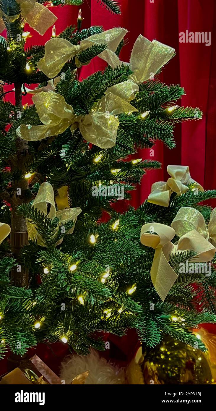 Weihnachtsbaum mit goldenen Bögen und Girlande auf rotem Hintergrund. Stockfoto
