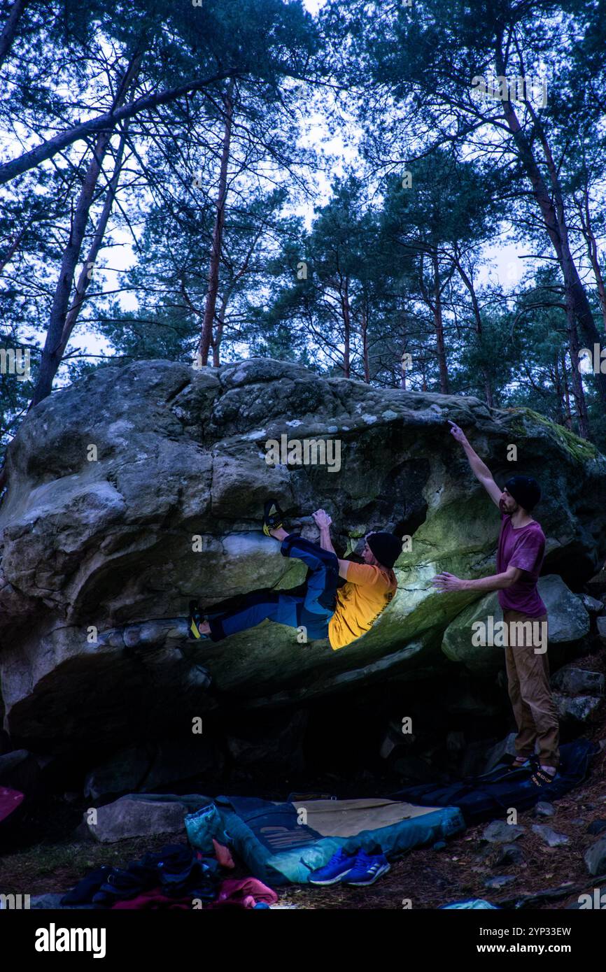 Michael Bunel/Le Pictorium - BLOCKKLETTERN IM WALD VON FONTAINEBLEAU - 05/01/2016 - Frankreich/Fontainebleau - zwei Brüder üben Bouldern im Wald von Fontainebleau. Beim Bouldern geht es um das Klettern von weniger als 8 Meter hohen Felsen ohne die Hilfe eines Seils. Auf dem Boden platzierte Matratzen, sogenannte Crashpads, schützen vor Stürzen. Möglicherweise kann eine Person in das Gerät aufgenommen werden, um schwere Stürze zu verhindern; wir nennen ihn im Kletterjargon den Spotter. Fontainebleau ist weltweit als Wiege des Boulderns bekannt. Das Waldmassiv Fontainebleau begrüßt jeweils 4 Millionen Kletterer Stockfoto