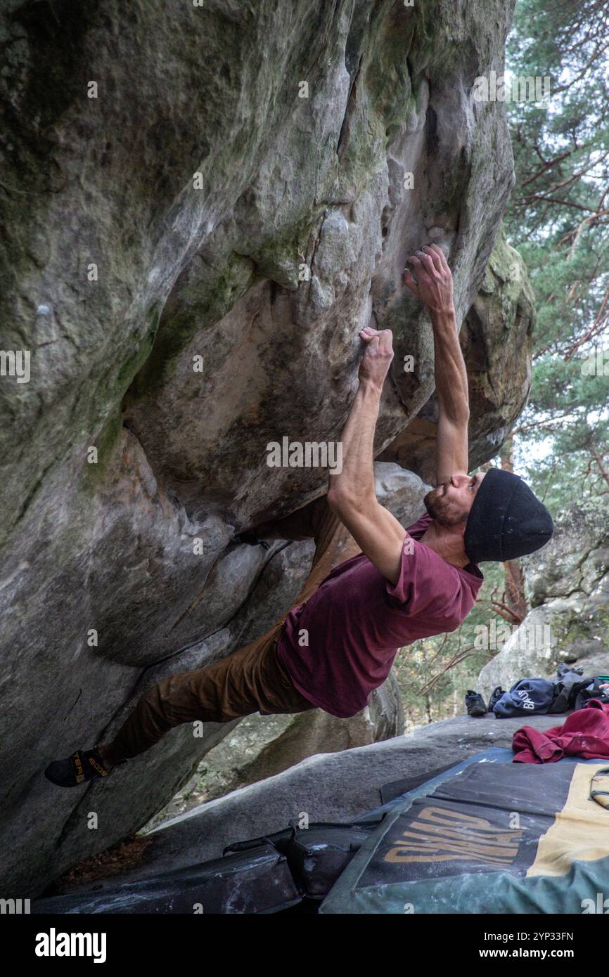 Michael Bunel/Le Pictorium - BLOCKKLETTERN IM WALD VON FONTAINEBLEAU - 05/01/2016 - Frankreich/Fontainebleau - zwei Brüder üben Bouldern im Wald von Fontainebleau. Beim Bouldern geht es um das Klettern von weniger als 8 Meter hohen Felsen ohne die Hilfe eines Seils. Auf dem Boden platzierte Matratzen, sogenannte Crashpads, schützen vor Stürzen. Möglicherweise kann eine Person in das Gerät aufgenommen werden, um schwere Stürze zu verhindern; wir nennen ihn im Kletterjargon den Spotter. Fontainebleau ist weltweit als Wiege des Boulderns bekannt. Das Waldmassiv Fontainebleau begrüßt jeweils 4 Millionen Kletterer Stockfoto