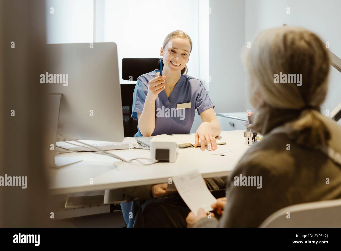 Ärztin sitzt mit Seniorin am Schreibtisch in der Klinik Stockfoto