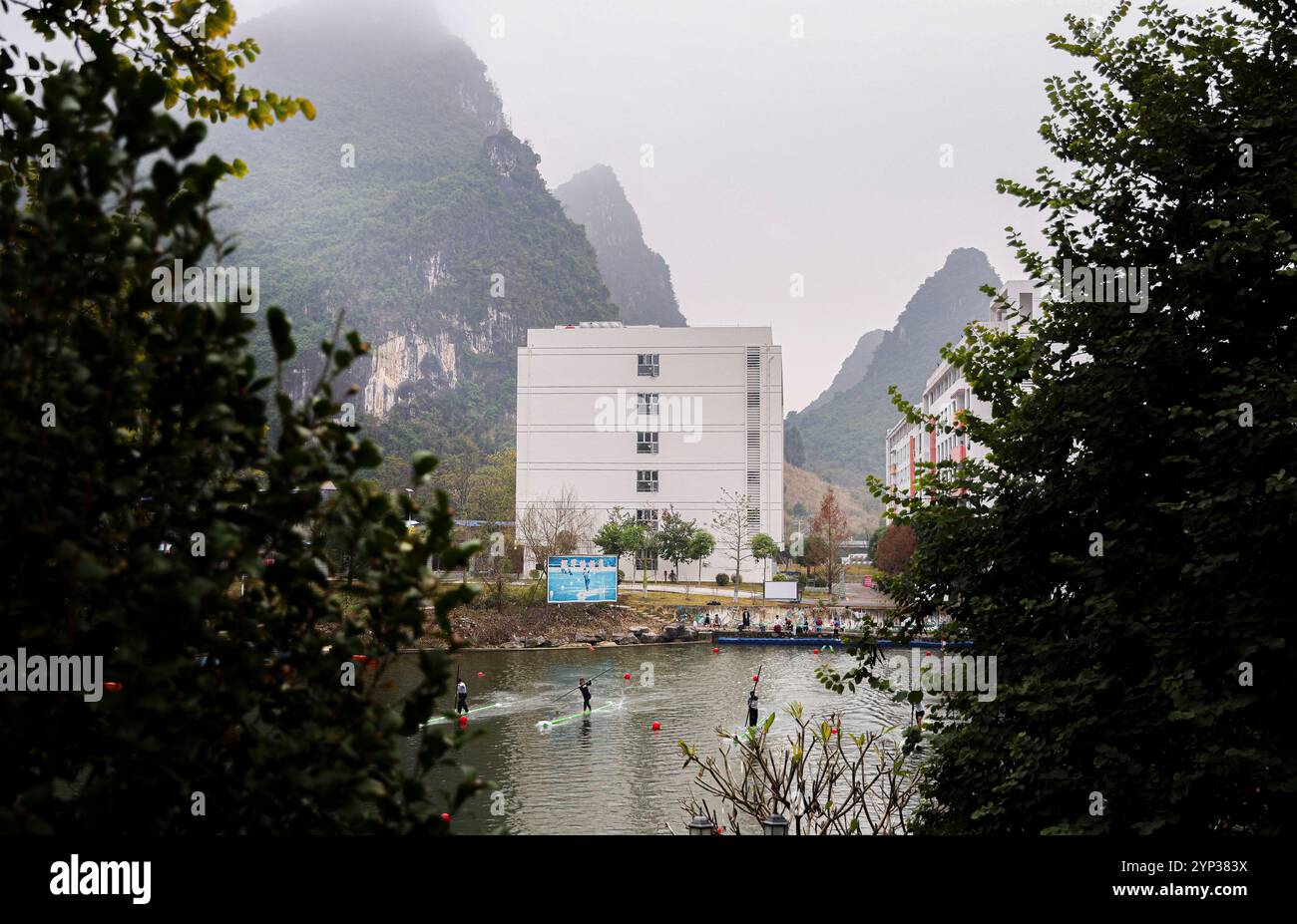 (241128) -- SANYA, 28. November 2024 (Xinhua) -- die Mitglieder des Teams für das Driften einzelner Bambus der Hechi University üben am Ausbildungsort der Universität in Hechi City, südchinesischer Autonomen Region Guangxi Zhuang, 9. Januar 2024. In Sanya, südchinesischer Provinz Hainan, hielt eine Gruppe junger Menschen lange Stöcke und trat auf Bambus auf dem Sanya-Fluss und ruderte flussaufwärts zur Ziellinie. Sie waren die Athleten der einzelnen Bambus-Drifing-Veranstaltung bei den 12. Nationalen traditionellen Spielen ethnischer Minderheiten Chinas. Die Veranstaltung dauerte vom 27. Bis 28. November. Während der Veranstaltung gewann das Team Guangxi Stockfoto