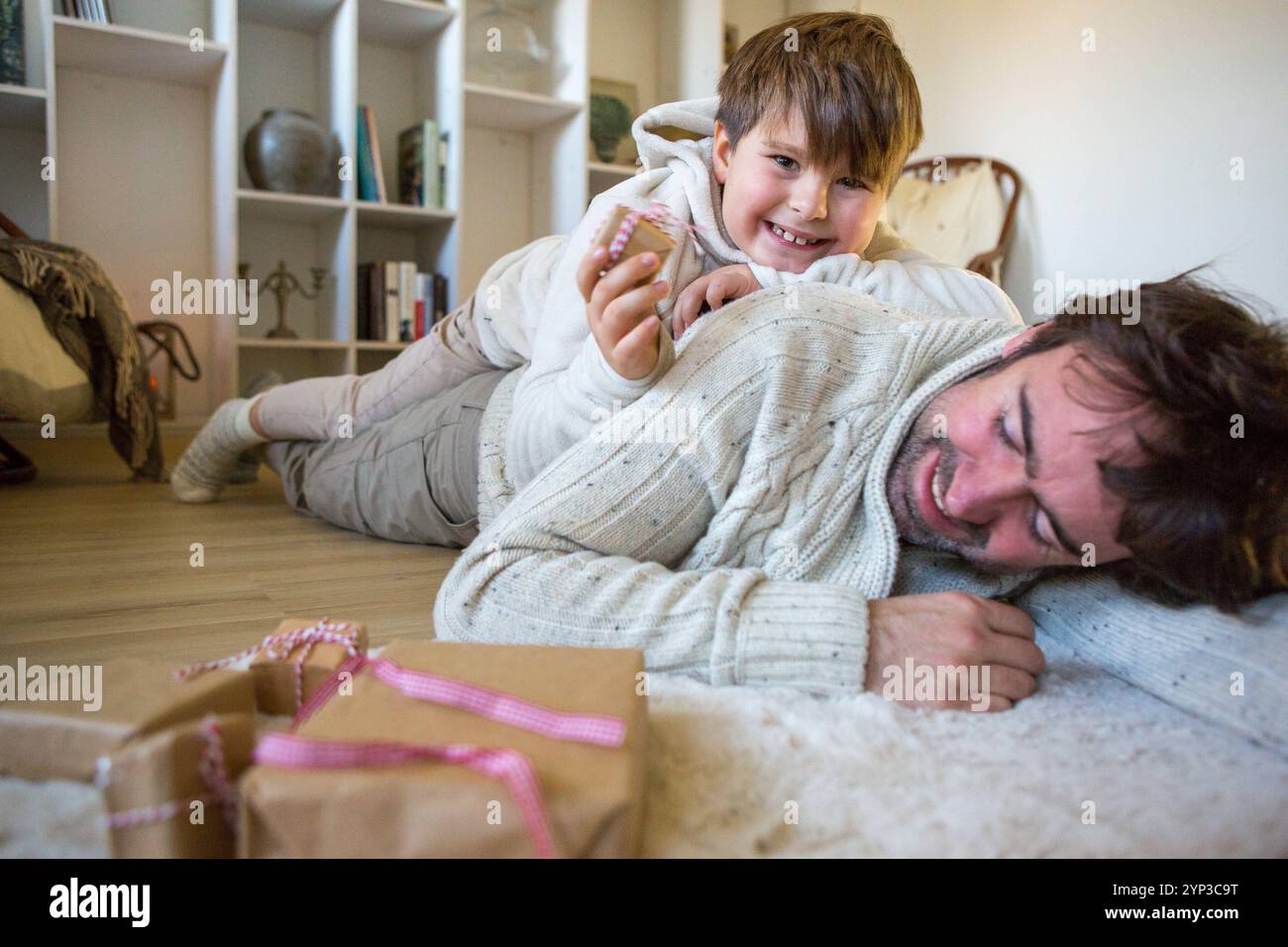 23. November 2024: Es macht mehr Spaß zusammen: Vater und Sohn genießen die verspielte Geschenkverpackung - Chaos und Lachen inklusive. *** Gemeinsam macht es mehr Spaß: Vater und Sohn genießen das spielerische Geschenkverpacken Chaos und Lachen inklusive Stockfoto