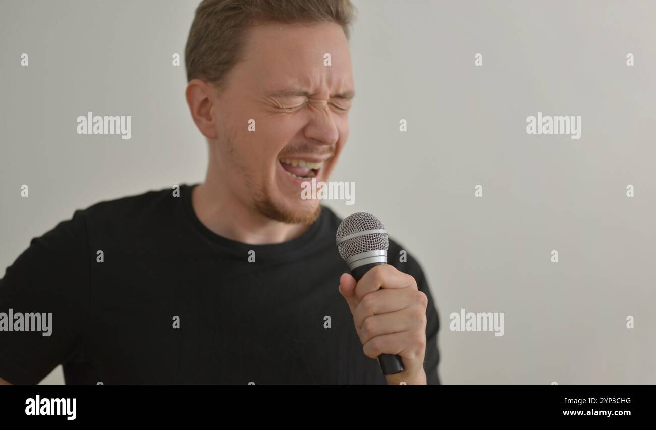 Ein Mann singt emotional im Mikrofon mit geschlossenen Augen. Stockfoto