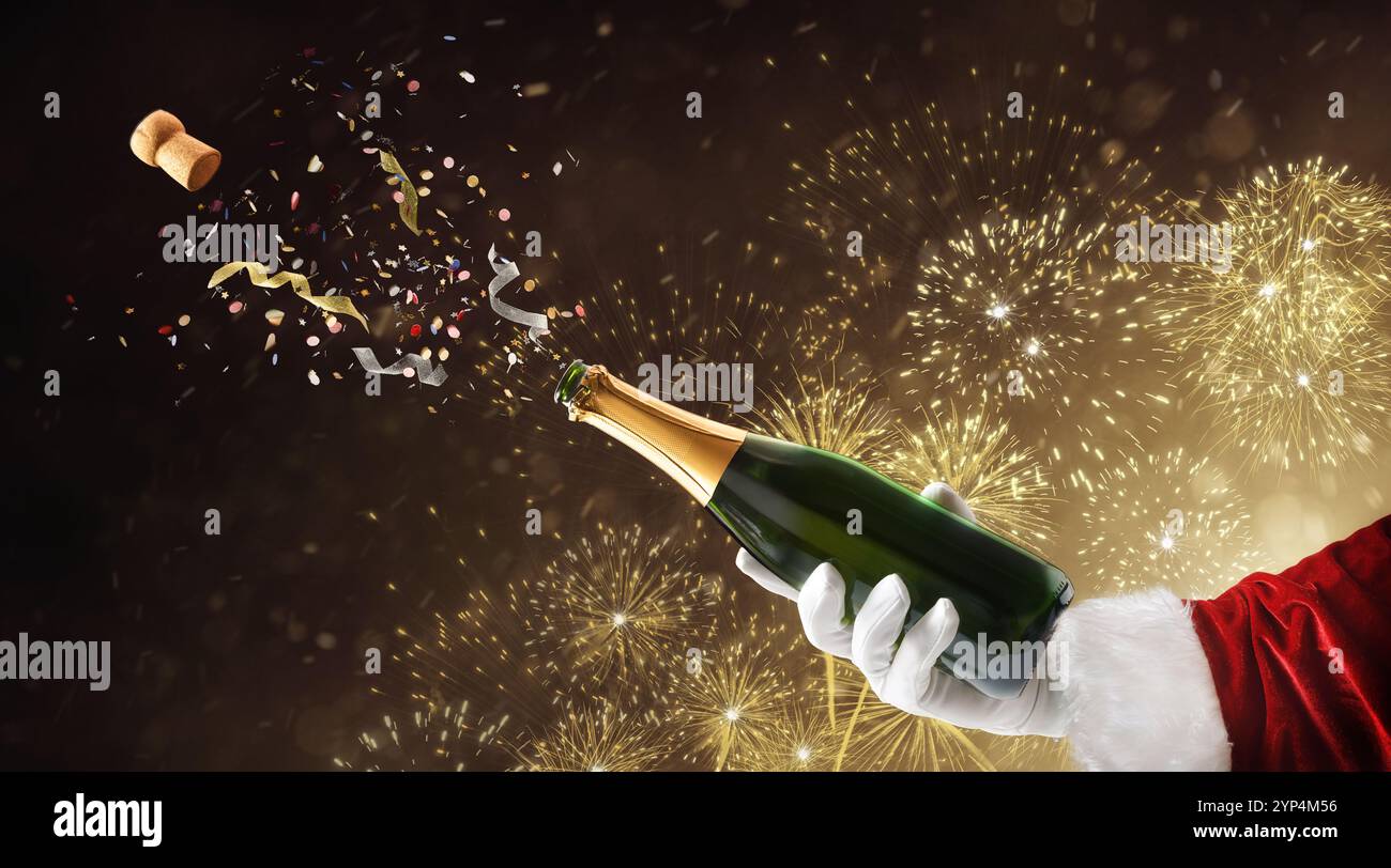 Weihnachtsmann Hand in Anzug und Handschuhe, die eine Flasche Champagner mit Konfetti und Feuerwerk im Hintergrund auskorken. Stockfoto