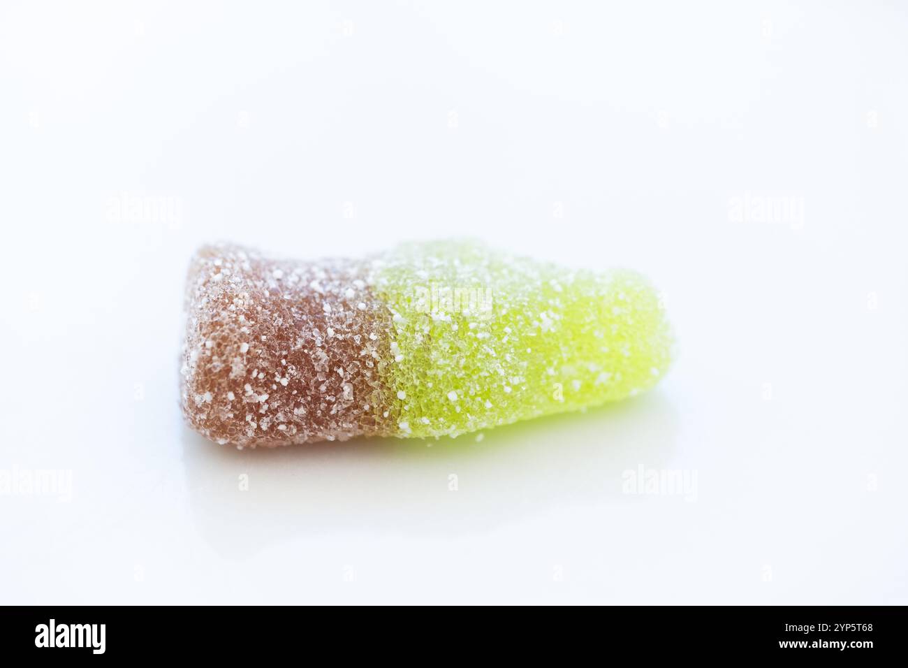 Detailstudio, aufgenommen von oben aus einer Cola-Flasche aus Jelly Beans mit Zucker darauf. Es ist auf einem sauberen weißen Hintergrund. Konzept von süßem Essen, süß Stockfoto