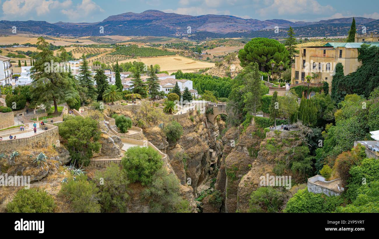 Puente Viejo Brücke in Ronda, mit mehreren Terrassen und Aussichtspunkten, mit Feldern und Bergen im Hintergrund Stockfoto