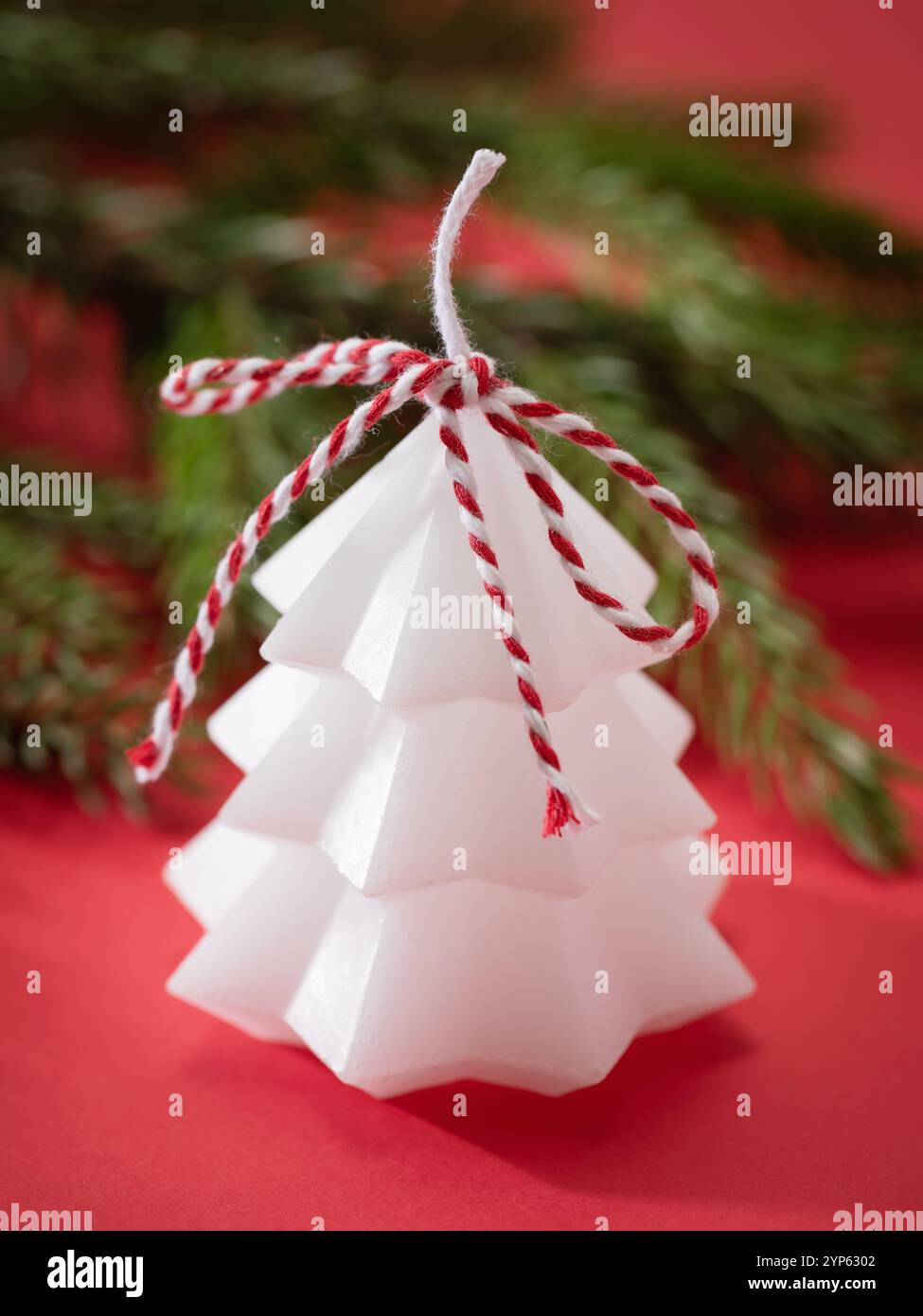 Weiße dekorative Kerze in Form eines Weihnachtsbaums auf farbigem Hintergrund Stockfoto